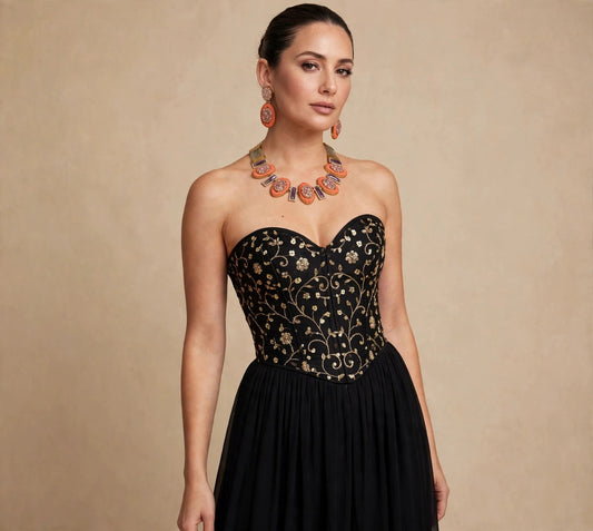 Model wearing the coral blush oval necklace set with matching earrings, black vine-embroidered corset and long black skirt