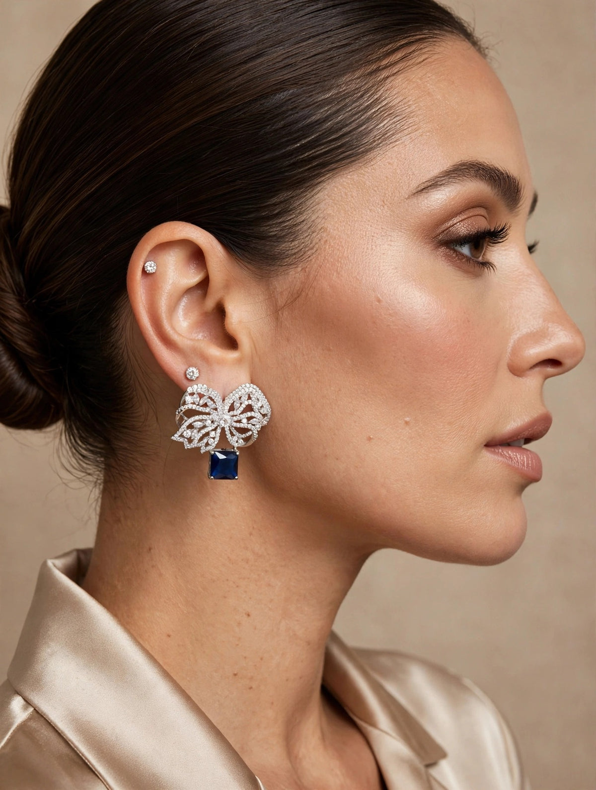 Model wearing the sapphire blue pavé crystal bow drop earrings, side profile