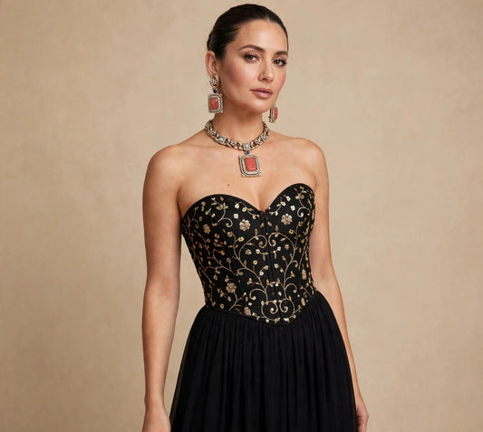 Model wearing the coral pendant link necklace set with matching earrings, black vine-embroidered corset and long black skirt